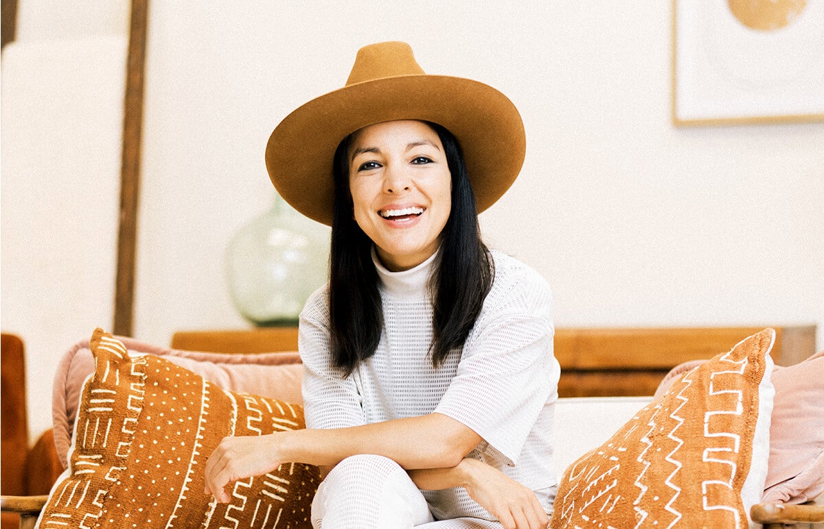Miki Agrawal sitting on an orange couch, arms crossed, smiling